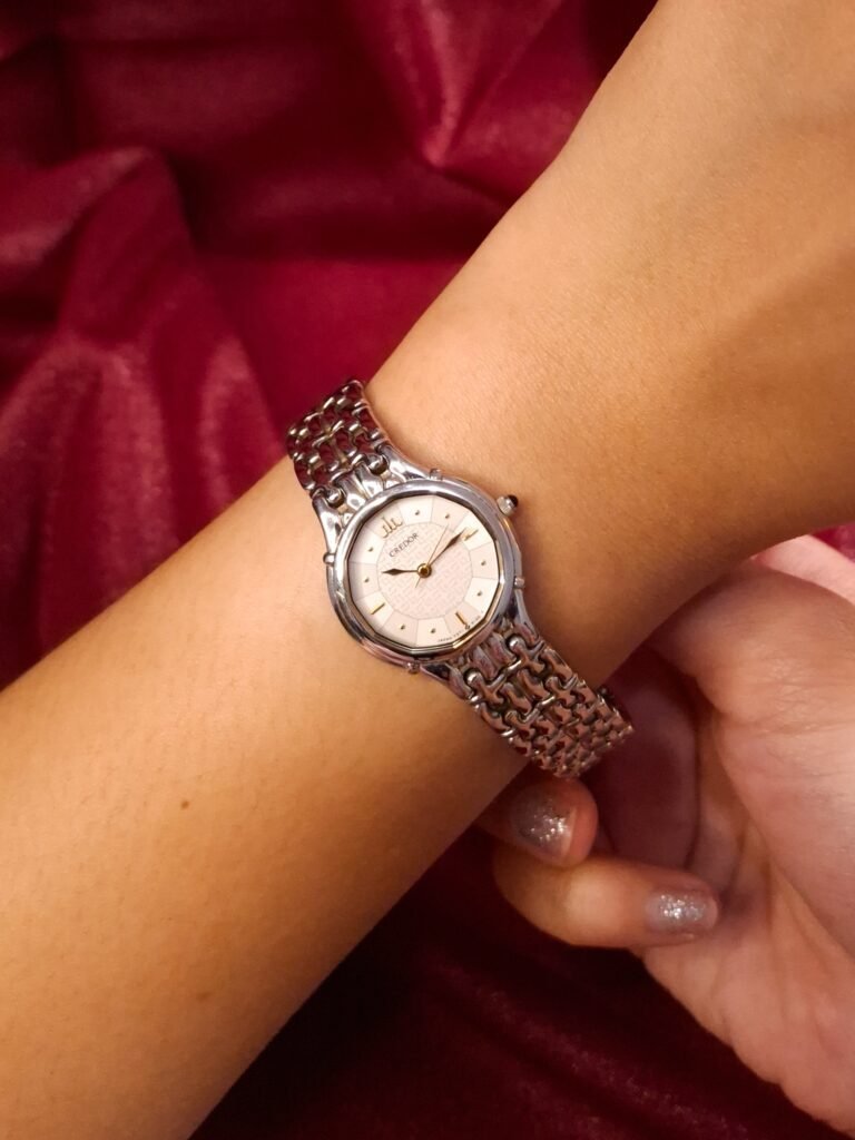 A hand holding a gold-tone vintage watch